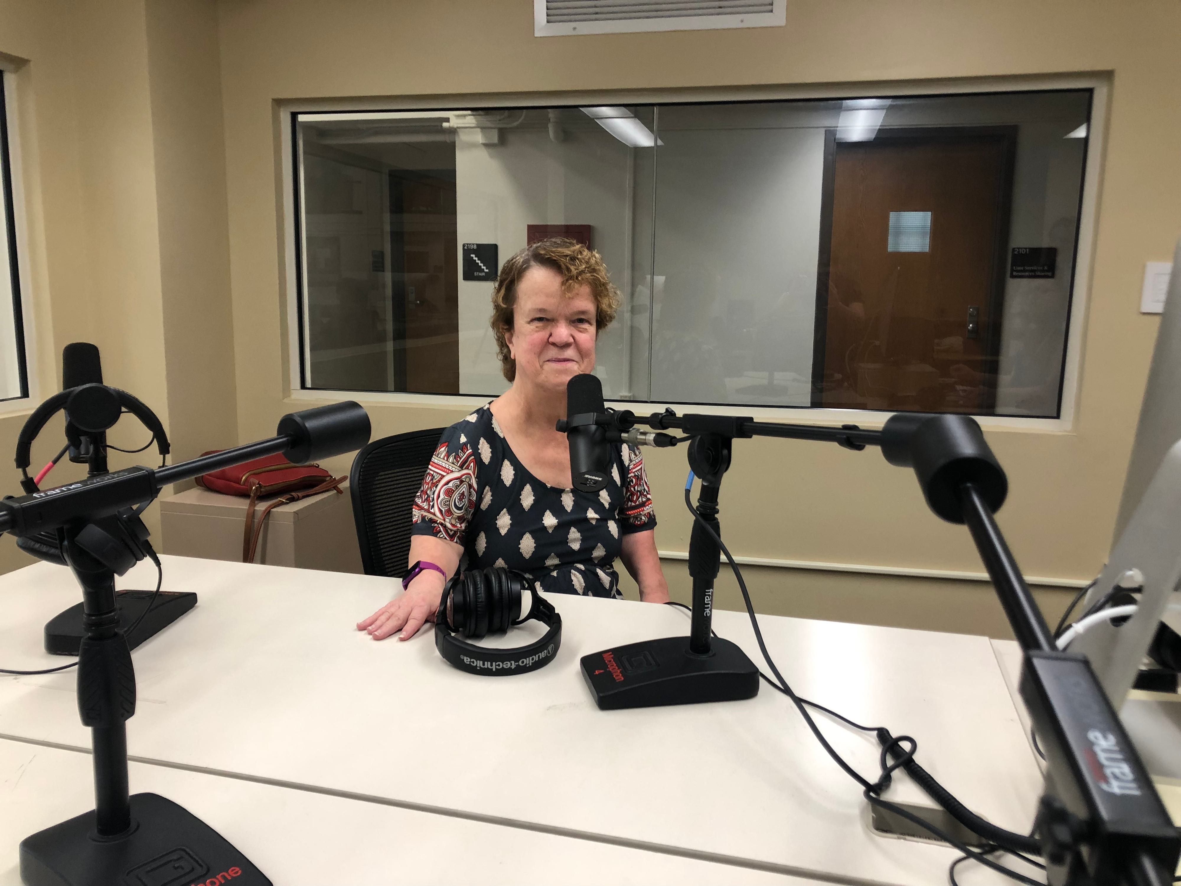 Portrait of Marie Trottier sitting in front of a microphone in a podcasting studio