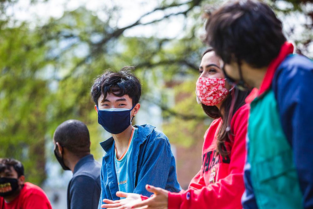 Students having discussions with each other outdoors on campus. One appears to be gesturing while talking