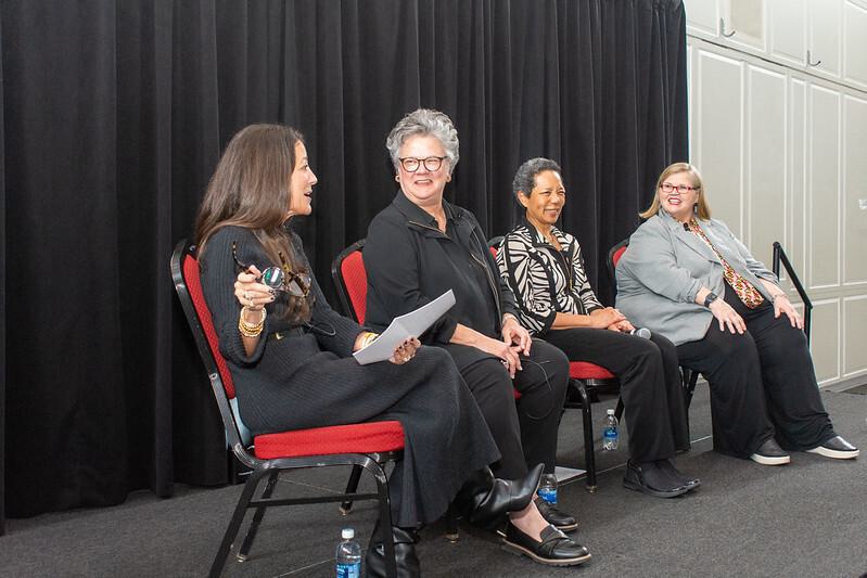 The panelists sitting on stage. Cate Luzio is gesturing with her glasses and Anne Buckley, Georgina Dodge and Patty Perillo are smiling