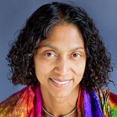 smiling light-skinned brown woman with curly black hair above the shoulder